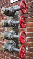 Red fire pump valves on a brick wall