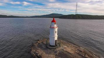 Seascape con un faro junto al cuerpo de agua con nublado cielo azul en Vladivostok, Rusia foto