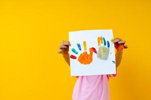 Niño sosteniendo arte en papel sobre fondo amarillo foto