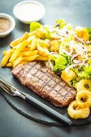 Grilled beef steak with french fries and fresh vegetables photo