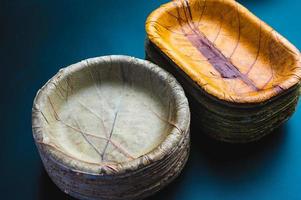 Stack of biodegradable eco-friendly paper plates next to stack of bowls made of leaves photo