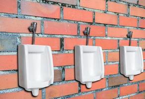 Tres urinarios contra la pared de ladrillo