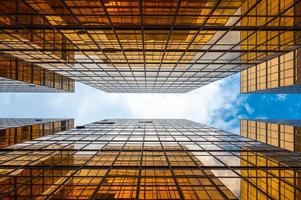 View looking up at skyscrapers with cloudy blue sky photo