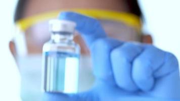 Arzthand in blauen Handschuhen, die eine Impfstoffflasche im Krankenhaus halten. video