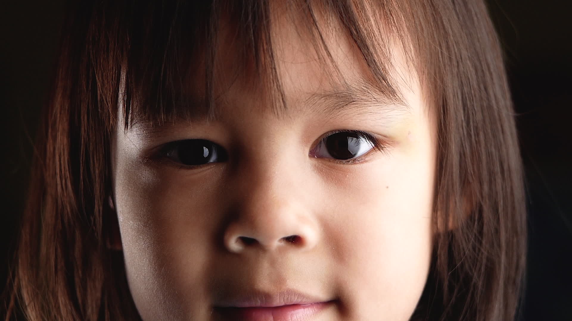 Close-up face portrait of cute little girl looking at the camera ...