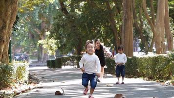 feliz madre y sus hijas jugando y riendo en el parque de verano. video