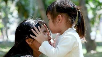 Feliz madre abrazando a su pequeña hija sonriendo en el césped video