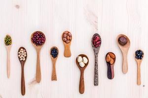 Frijoles y lentejas en cucharas de madera sobre fondo de madera foto