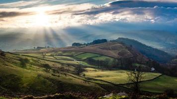 Vista aérea del paisaje de colinas y árboles con sol bajo en un cielo nublado foto