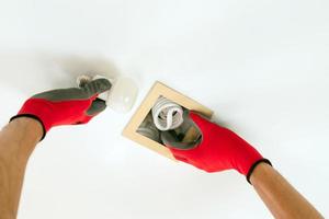 Dos manos en guantes reemplazando una bombilla fluorescente con bombilla led foto