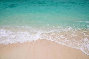 olas espumosas y agua azul en una playa foto