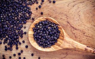 Close-up of black peppers in a wooden spoon photo