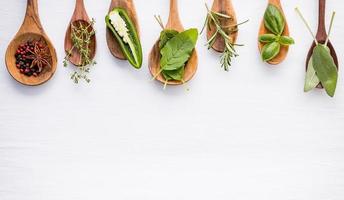 Spices and herbs in spoons on white photo