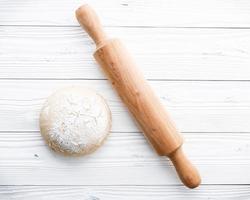 Pizza dough and rolling pin on white wooden background photo