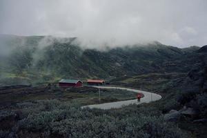 Cyclist riding into foggy mountains towards red barn photo