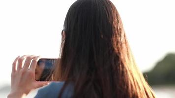 Frau, die ein Smartphone benutzt, um ein Foto am Strand zu machen video