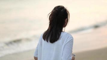 Mujer con una camisa blanca caminando por la playa tropical video