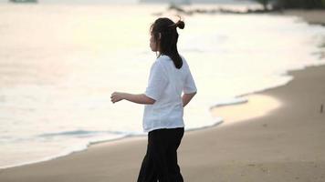 mulher asiática caminhando em uma praia tropical ao pôr do sol video