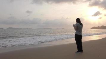 alleen vrouw staande op tropisch strand in zonsondergang licht. video