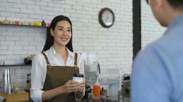 Unternehmenskonzept. Barista gibt Kunden Kaffee mit einem Lächeln. 4k Auflösung.