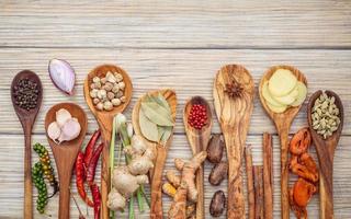 Herbs and spices in spoons on a light wooden background photo