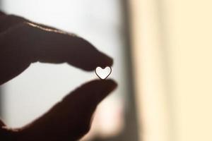 Person holding a small heart shape photo