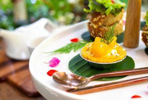 Mango tart mini is served on a white plate and adorned with beautiful flowers