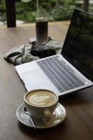 Hot coffee latte on a wooden table with a laptop