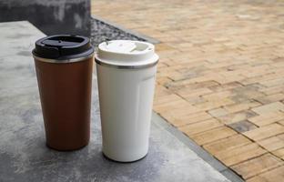 Two travel mugs on concrete photo
