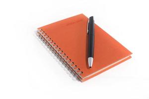 Orange notebook with black pen on white background photo