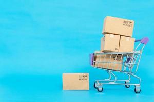 Paper boxes in a trolley on a blue background. Online shopping or e-commerce concept and delivery service concept with copy space for your design photo