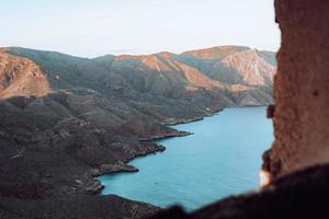 Montañas marrones y verdes junto al cuerpo de agua durante el día foto