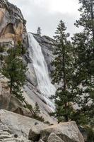 Waterfall against granite boulders and evergreens photo