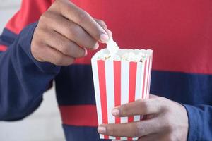 Young man eating popcorn close up photo