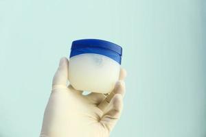 Gloved hand holding petroleum jelly photo
