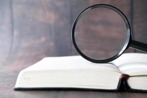 Open book and magnifying glass on table photo