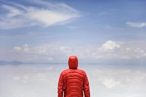 Young man in winter hooded jacket at Salar de uyuni salt flat in Bolivia photo