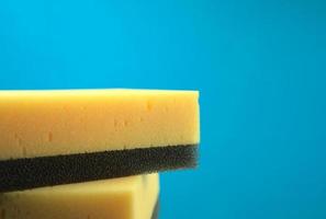 Yellow and black scouring pad sponges isolated with a blue background photo