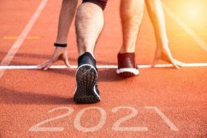 New year or start straight concept. Close up of an athlete runner running to success and new achievements on the path with 2021 inscription photo