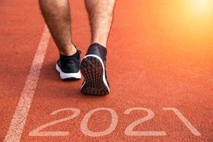 año nuevo o comenzar directamente el concepto. Cerca de un corredor atleta corriendo hacia el éxito y nuevos logros en el camino con inscripción 2021 foto