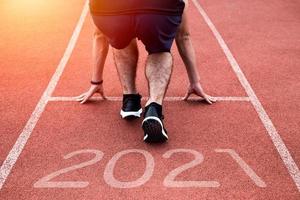 año nuevo o comenzar directamente el concepto. Cerca de un corredor atleta corriendo hacia el éxito y nuevos logros en el camino con inscripción 2021 foto