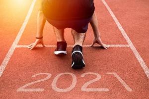 New year or start straight concept. Close up of an athlete runner running to success and new achievements on the path with 2021 inscription photo