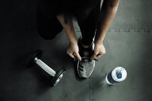 mujer atándose los cordones de los zapatos. Cerca del corredor de fitness deporte femenino preparándose para trotar en el gimnasio foto