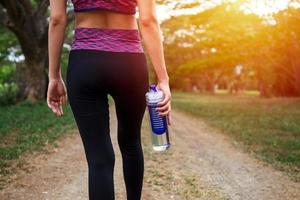 Una corredora de pie al aire libre sosteniendo una botella de agua, concepto saludable y deportivo foto