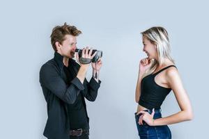 Happy portrait of couple holding video camera and recording a video