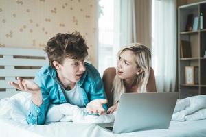 Happy couple using laptop computer on the bed photo