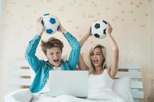 Happy couple watching soccer football on the bed photo