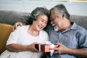 pareja de ancianos sorprende con caja de regalo en el salón foto