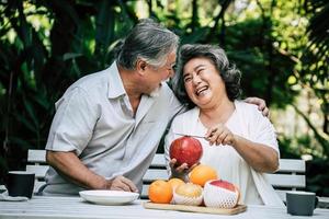 Elderly couple slicing and eating fruit