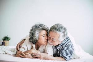 Happy senior couple laughing in bedroom photo